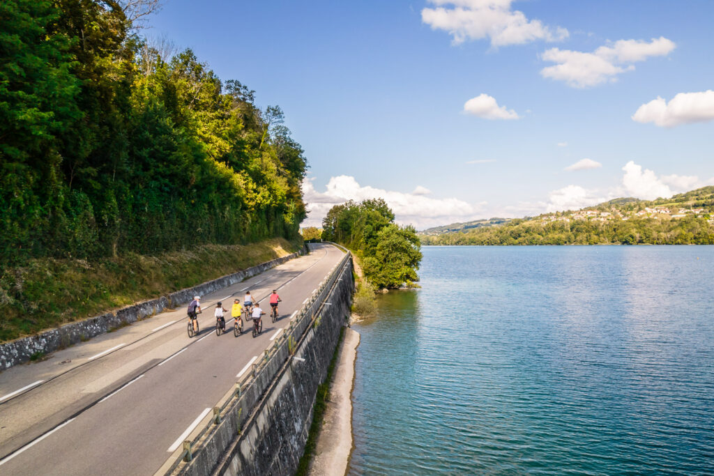 cyclistes roulant sur une route au bord d'un lac