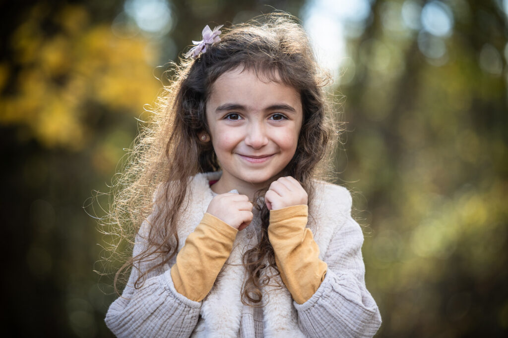 portrait d'une petite fille souriante réalisée séance photo enfant en extérieur par un photographe professionnel à Annecy à l'automne