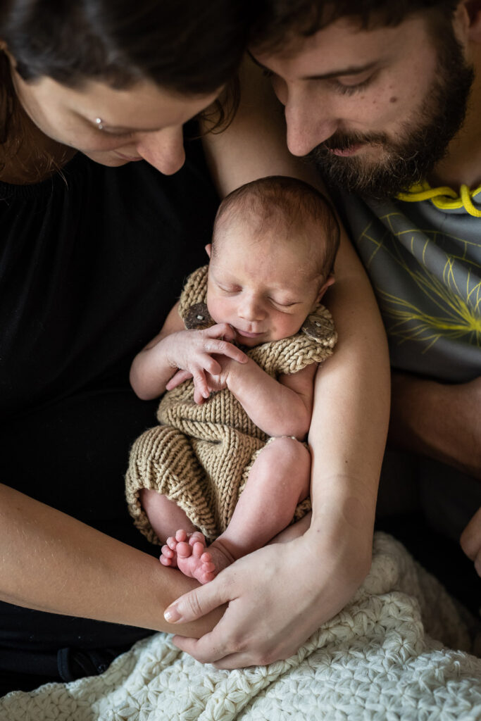 photo d'un nouveau né dans les bras de ses parents réalisée à domicile par un photographe professionnel à Chambéry