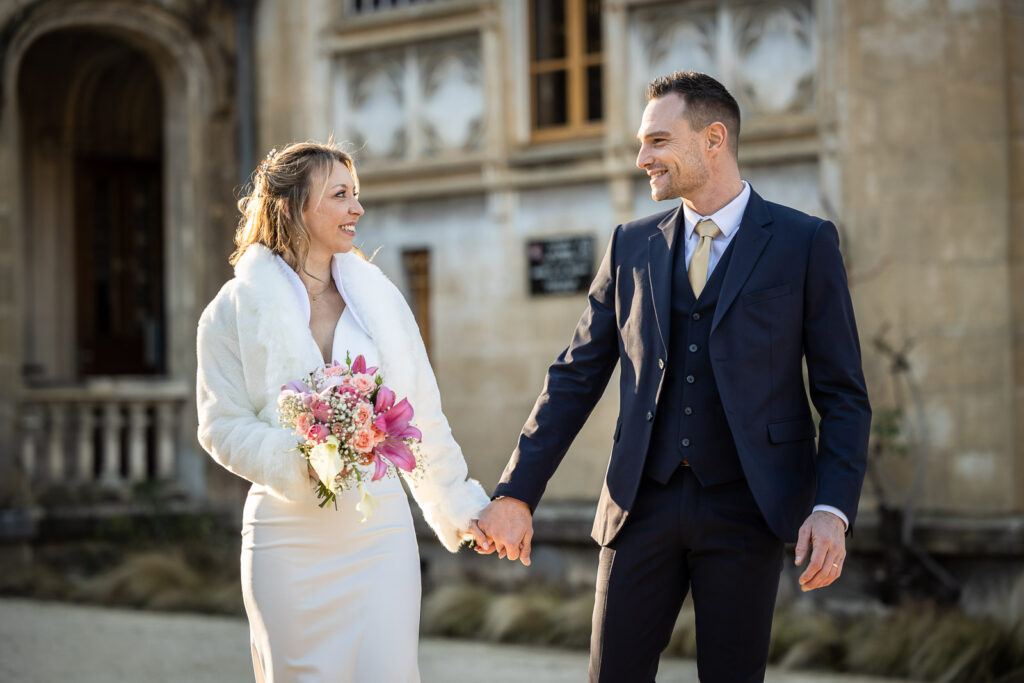 couple de jeunes mariés marchant devant un château, moment capturé par un photographe mariage à Chambéry