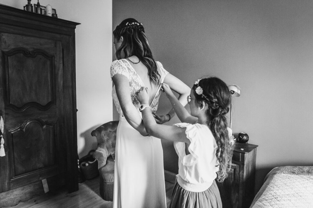 la future mariée est aidée par sa fille pour fermer la fermeture de sa robe de mariée, photo issue d'un reportage photo mariage par thomas vigliano