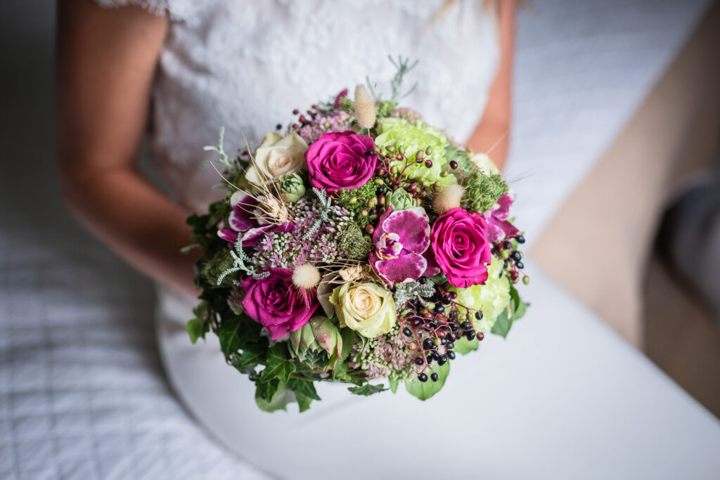 bouquet de la mariée avec des fleurs colorées vertes et violettes, photo en close up réalisée par un photographe spécialisé dans le mariage