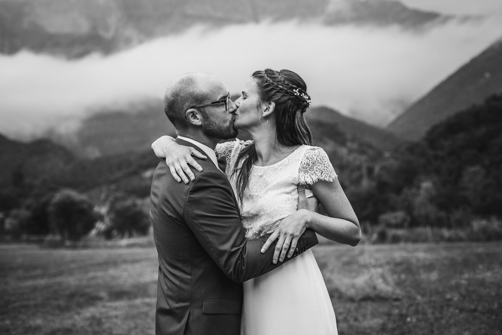 les mariés s'embrassent lors de leur séance couple le jour de leur mariage, avec en fond un paysage montagne magnifique