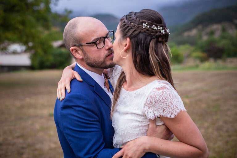 les mariés s'embrassent lors de leur séance couple le jour de leur mariage avec un photographe professionnel dans un cadre de verdure