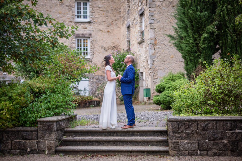 les mariés posent pour le photographe mariage devant la façade du domaine le jour de leur mariage