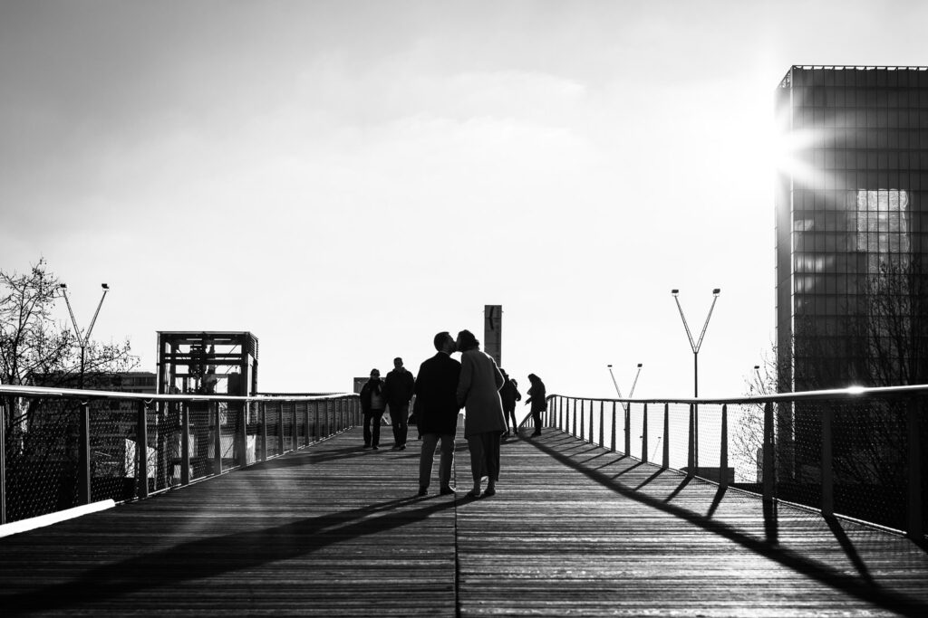 couple s'embrassant sur un pont parisien, photo en noir et blanc prise par un photographe lors d'une séance photo couple