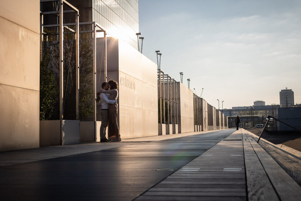 couple qui s'enlace sur le parvis d'un bâtiment à Paris, lors d'un shooting photo couple au coucher de soleil