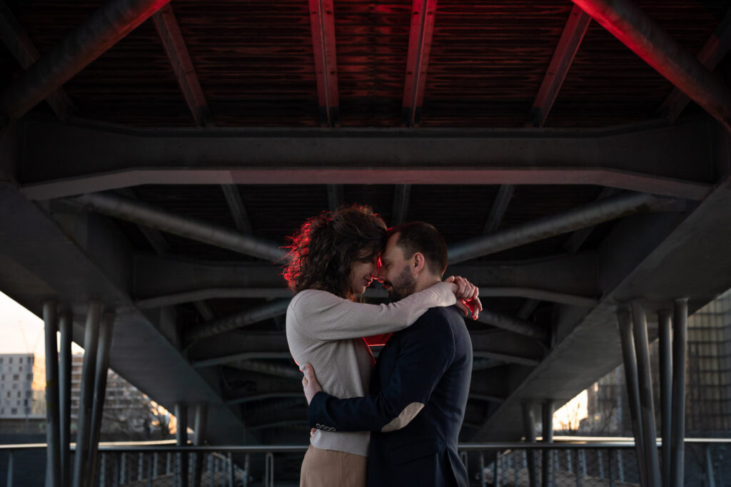 portrait artistique d'un couple qui s'embrasse sous un pont à Paris lors d'une session photo de couple avec un photographe professionnel