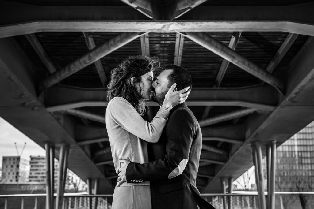 portrait artistique d'un couple qui s'embrasse sous un pont à Paris lors d'une session photo de couple avec un photographe professionnel