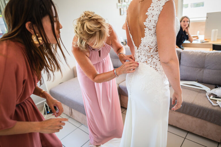 habillage de la mariée avec l'aide de ses témoins, photo réalisée par un photographe mariage en isère
