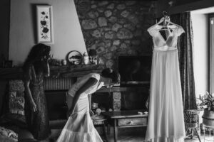 préparatifs de la mariée avec la témoin qui tient la robe de mariée